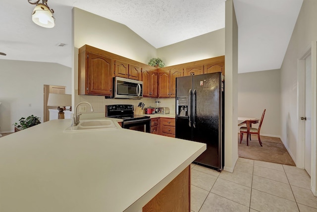 kitchen with lofted ceiling, sink, light tile patterned floors, black appliances, and kitchen peninsula