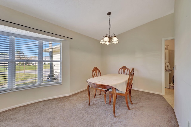 dining room featuring light colored carpet, lofted ceiling, and a chandelier