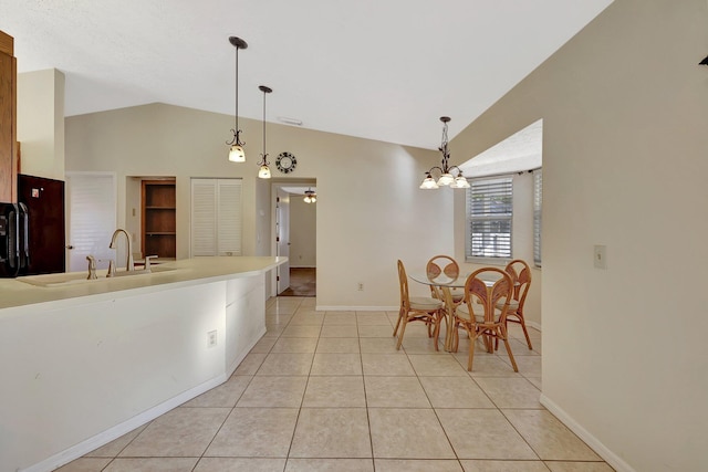 kitchen with pendant lighting, sink, light tile patterned floors, lofted ceiling, and ceiling fan with notable chandelier