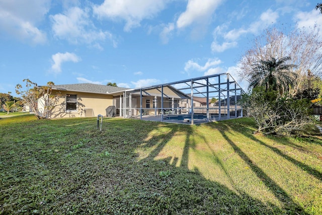 rear view of property with a yard, a patio area, and glass enclosure