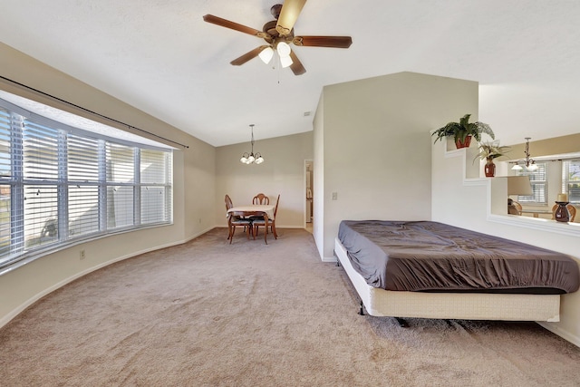 carpeted bedroom featuring ceiling fan with notable chandelier and vaulted ceiling