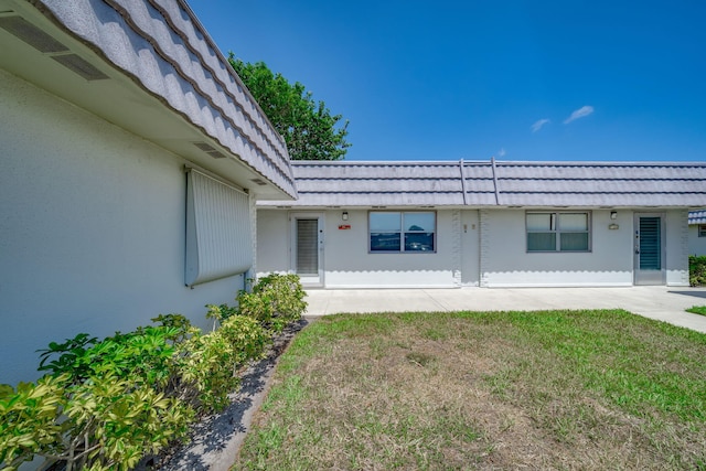 8 Valencia Unit A, Delray Beach, FL 33446 - view of exterior entry featuring mansard roof, stucco siding, and a yard