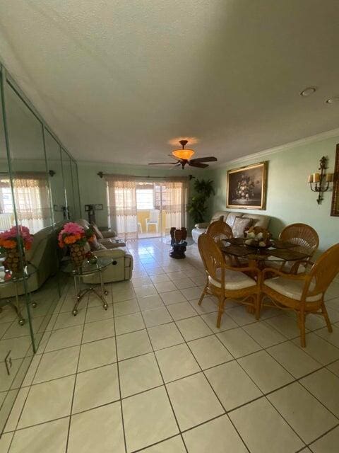 tiled dining space featuring a textured ceiling, ornamental molding, and ceiling fan