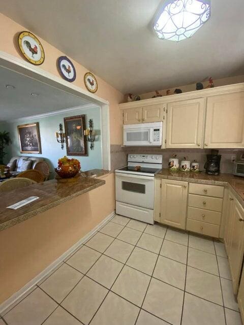 kitchen featuring light tile patterned flooring, ornamental molding, and white appliances