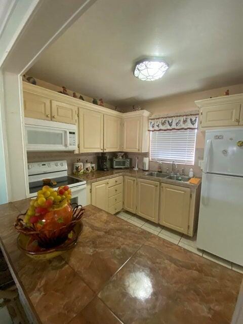 kitchen featuring cream cabinets, sink, light tile patterned floors, and white appliances