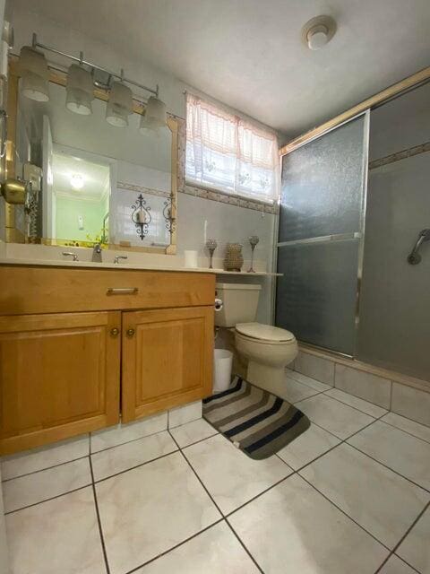 bathroom with walk in shower, vanity, toilet, and tile patterned flooring