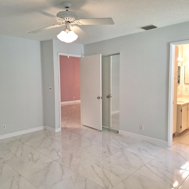 empty room with ceiling fan and a textured ceiling