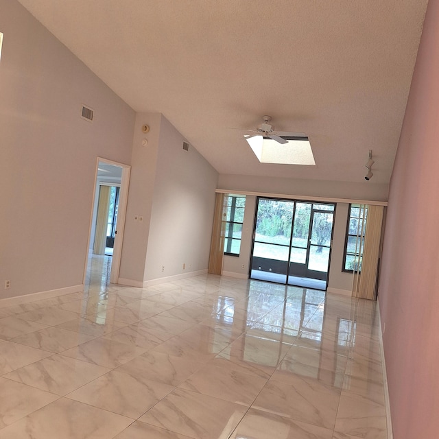 unfurnished room featuring a textured ceiling, a skylight, high vaulted ceiling, and ceiling fan