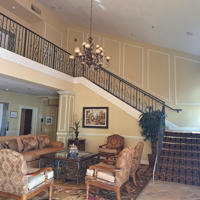 living room with a high ceiling, an inviting chandelier, and ornate columns