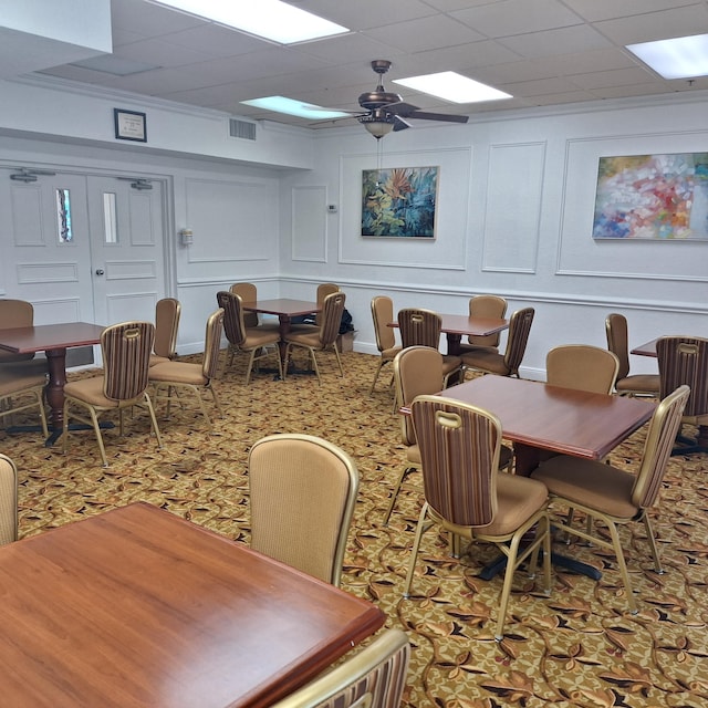 carpeted dining room with a drop ceiling and ceiling fan