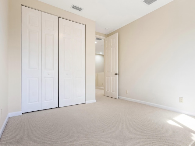 unfurnished bedroom with light colored carpet and a closet