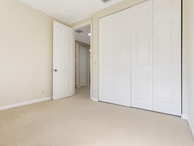 unfurnished bedroom with light colored carpet and a closet