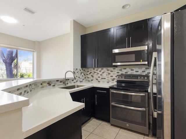 kitchen featuring light tile patterned floors, stainless steel appliances, sink, and backsplash