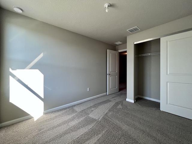 unfurnished bedroom with a closet, a textured ceiling, and dark colored carpet