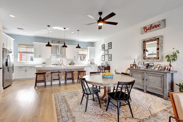 dining room featuring ceiling fan, sink, and light wood-type flooring