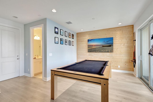 game room with light wood-type flooring and wood walls