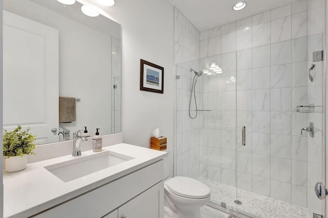 bathroom with vanity, a shower with door, and toilet