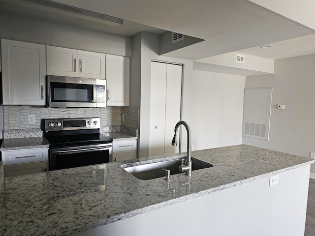 kitchen with sink, appliances with stainless steel finishes, tasteful backsplash, light stone countertops, and white cabinets