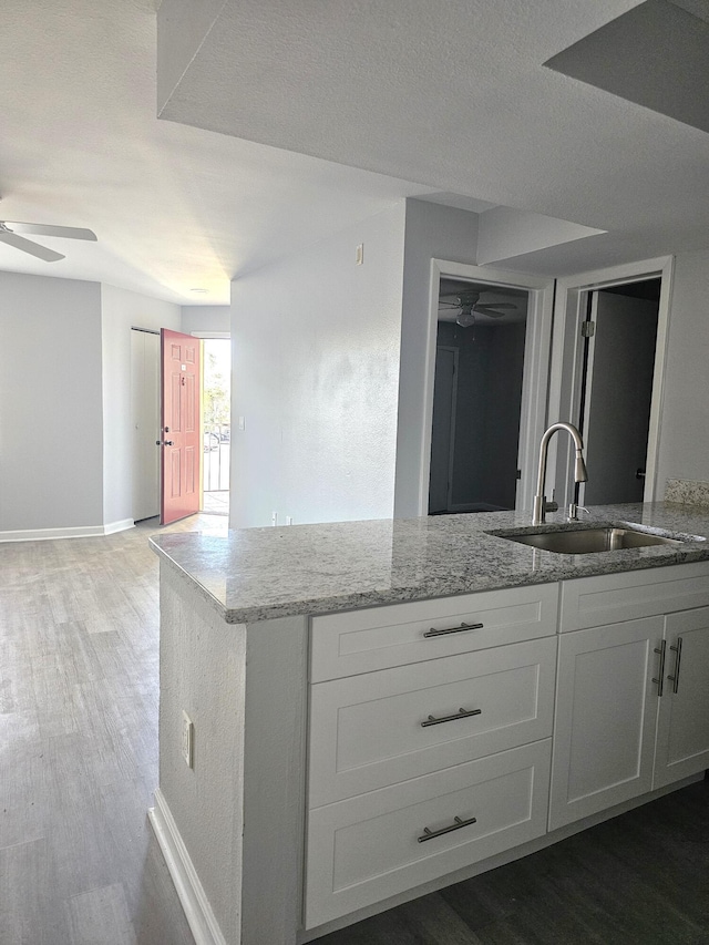 kitchen featuring white cabinetry, sink, hardwood / wood-style floors, and light stone counters