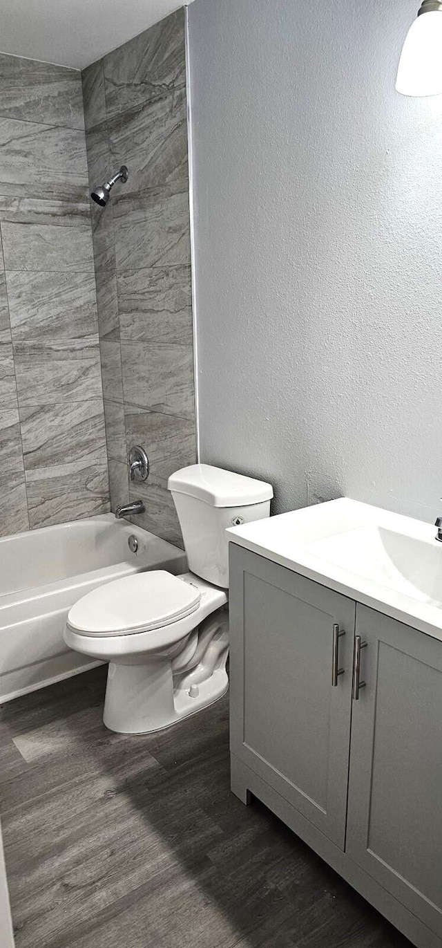 full bathroom with vanity, hardwood / wood-style floors, tiled shower / bath, and toilet