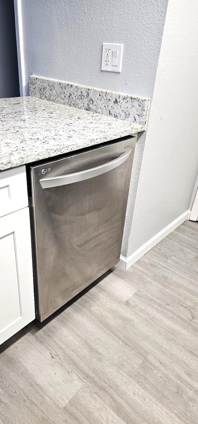 details featuring white cabinetry, light stone countertops, stainless steel dishwasher, and light hardwood / wood-style floors