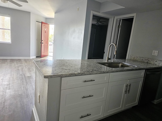 kitchen with sink, ceiling fan, hardwood / wood-style floors, light stone countertops, and white cabinets