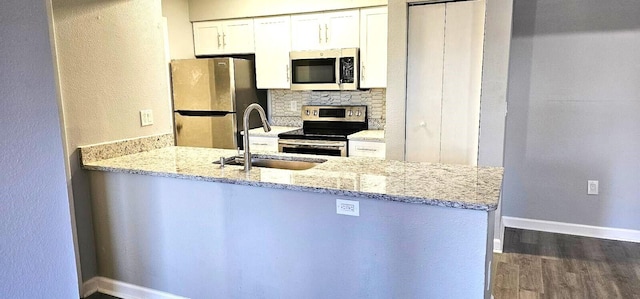 kitchen with white cabinetry, sink, kitchen peninsula, stainless steel appliances, and light stone countertops