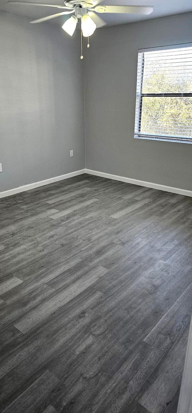 spare room featuring dark wood-type flooring and ceiling fan