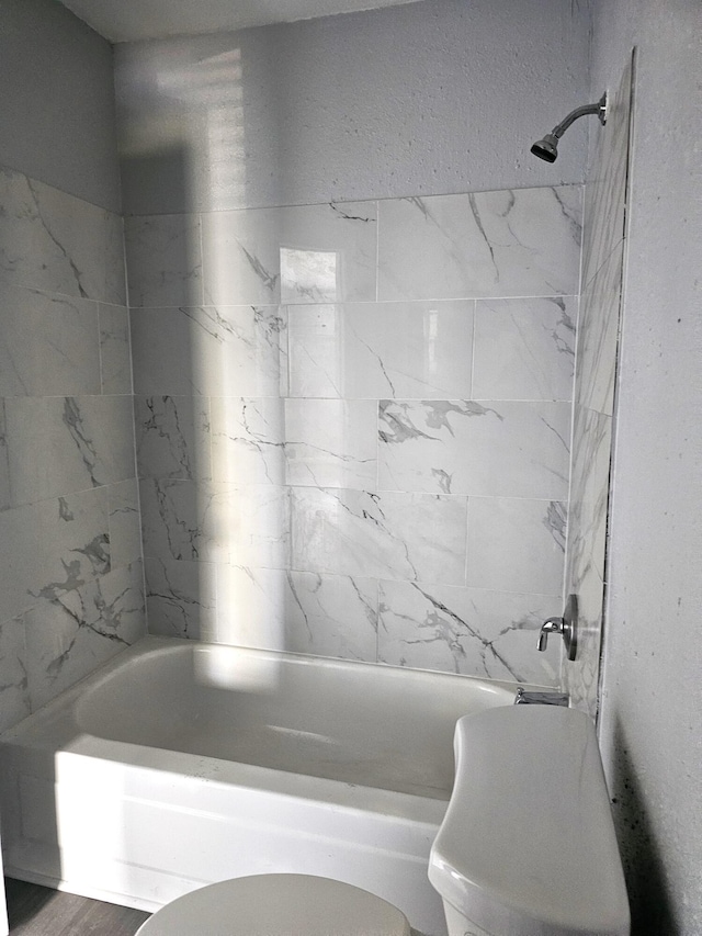 bathroom featuring tiled shower / bath and toilet