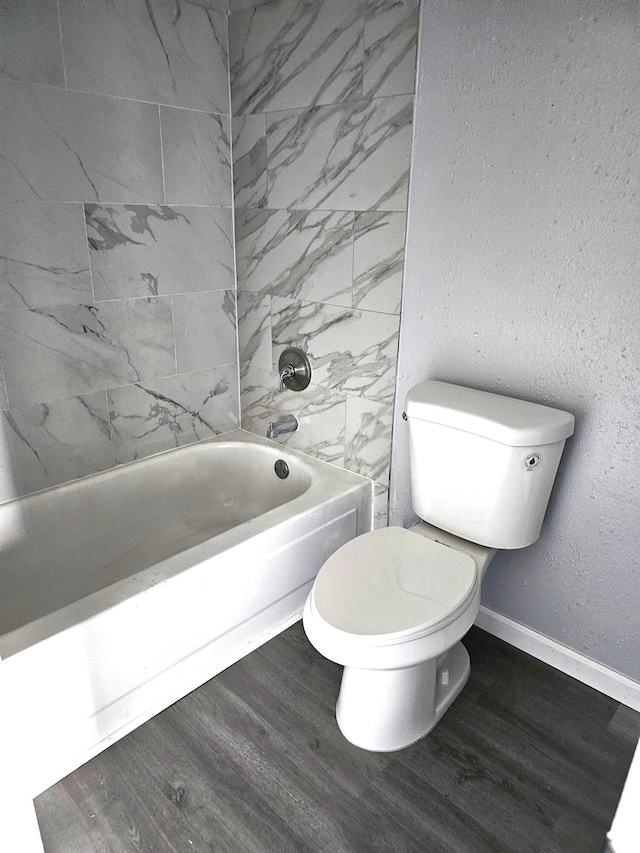 bathroom with tiled shower / bath, wood-type flooring, and toilet