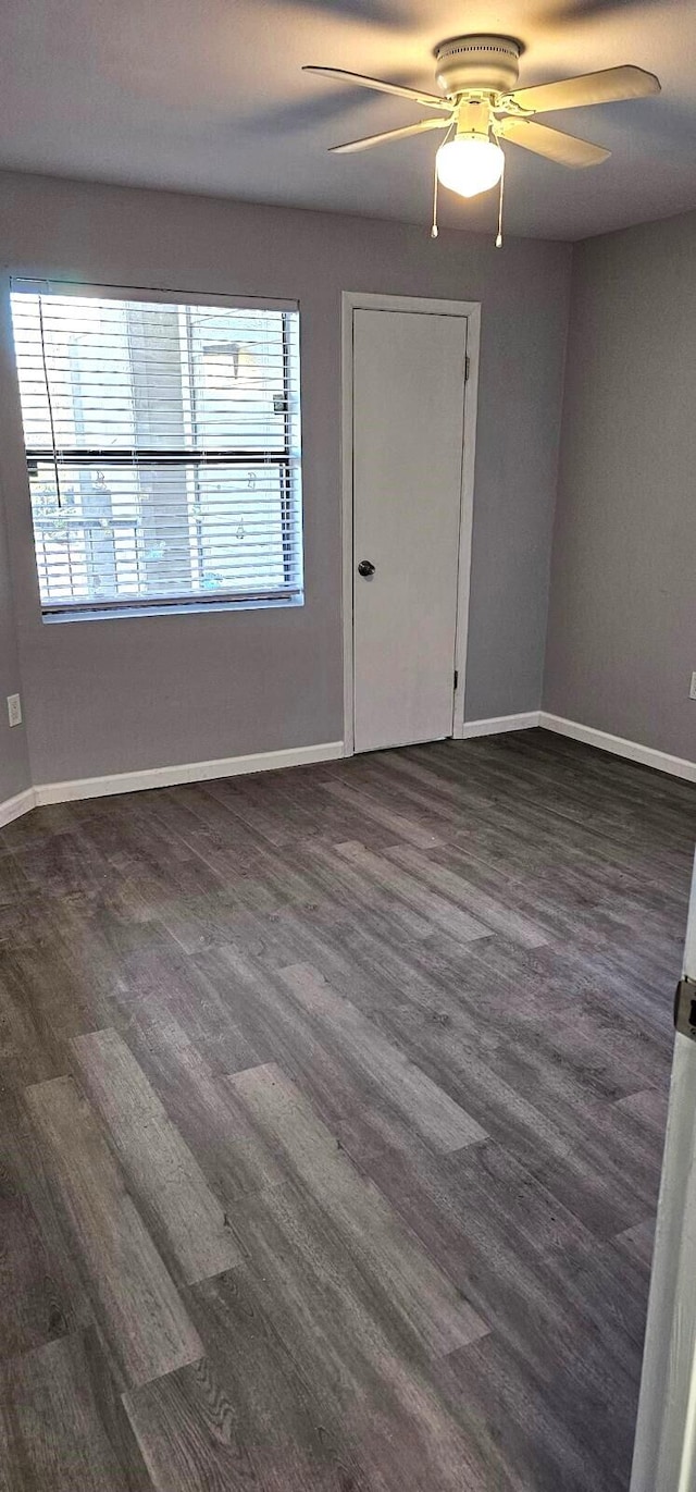 empty room featuring ceiling fan, plenty of natural light, and dark hardwood / wood-style flooring