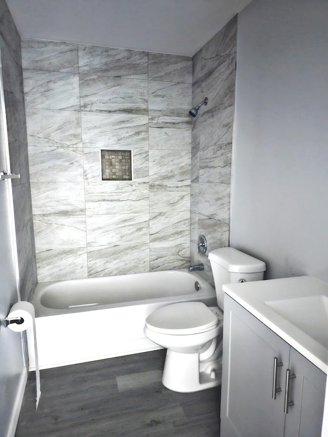 full bathroom with vanity, wood-type flooring, toilet, and tiled shower / bath