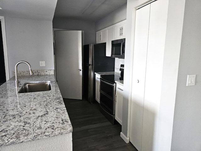 kitchen with sink, light stone counters, white cabinets, dark hardwood / wood-style flooring, and range with two ovens