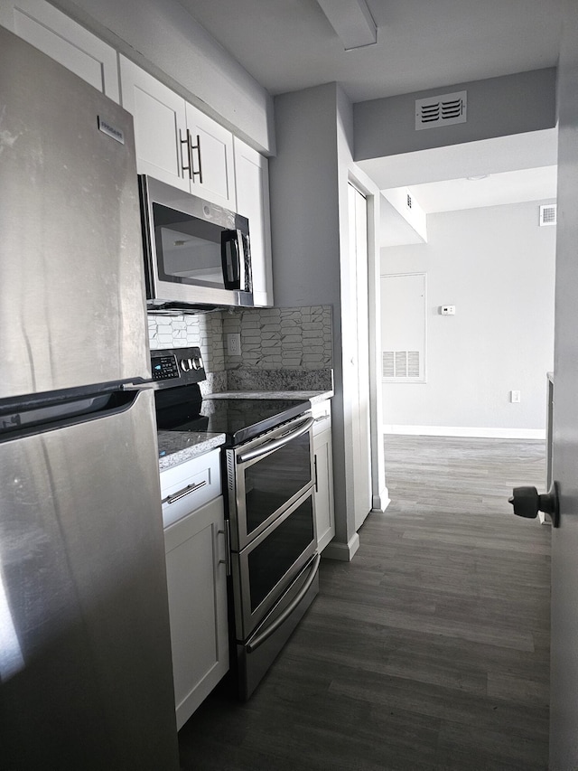 kitchen with white cabinetry, stainless steel appliances, dark hardwood / wood-style flooring, and tasteful backsplash