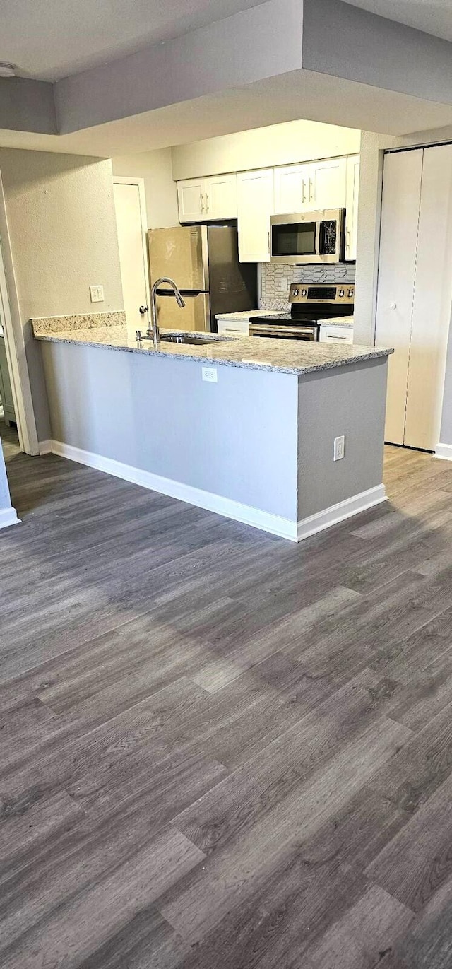 kitchen featuring dark hardwood / wood-style flooring, light stone countertops, white cabinets, and appliances with stainless steel finishes