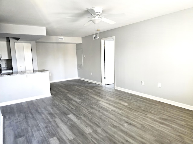 unfurnished living room featuring dark wood-type flooring and ceiling fan