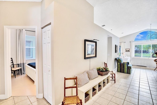 corridor featuring light tile patterned floors, vaulted ceiling, and a textured ceiling