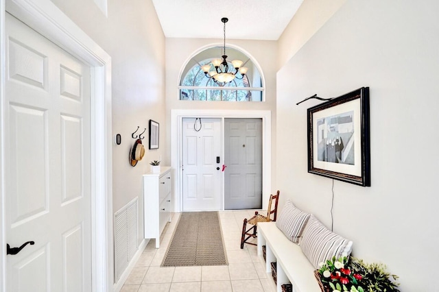 entryway with light tile patterned floors and an inviting chandelier