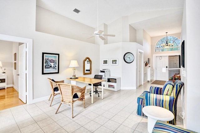 tiled dining space with ceiling fan with notable chandelier and high vaulted ceiling