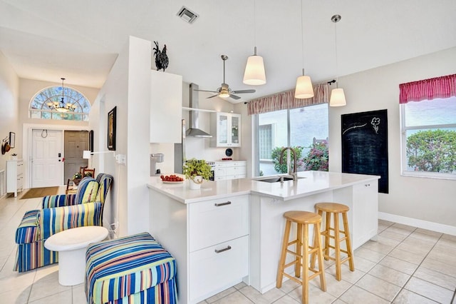 kitchen featuring white cabinetry, sink, wall chimney range hood, and a healthy amount of sunlight