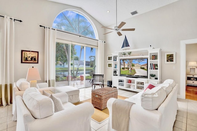 living room featuring light tile patterned flooring, ceiling fan, high vaulted ceiling, and a textured ceiling