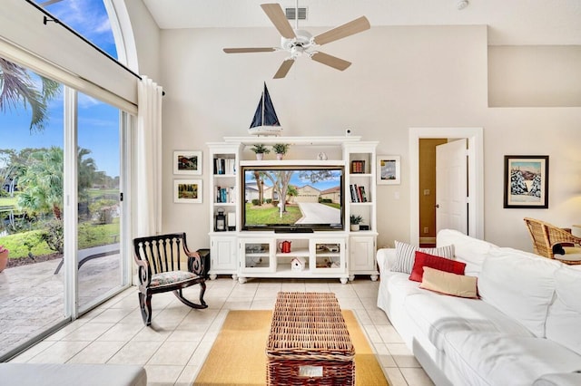 living room with ceiling fan, a towering ceiling, and light tile patterned floors