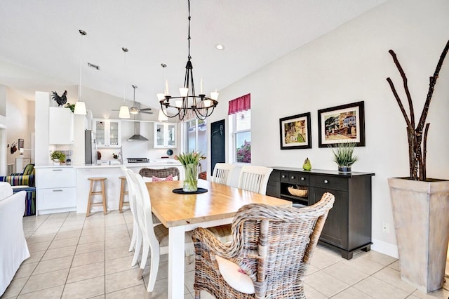 dining space with light tile patterned flooring, ceiling fan with notable chandelier, and high vaulted ceiling