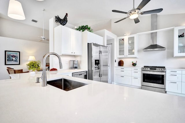 kitchen with vaulted ceiling, white cabinetry, sink, stainless steel appliances, and wall chimney exhaust hood