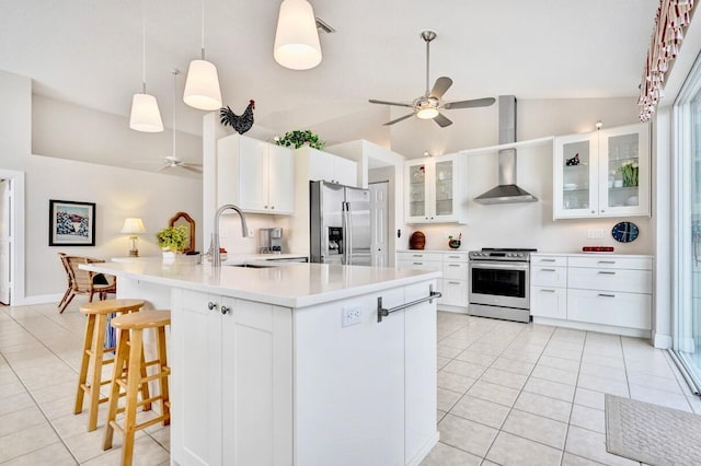 kitchen featuring wall chimney range hood, sink, ceiling fan, stainless steel appliances, and white cabinets