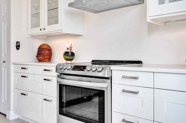 kitchen featuring white cabinetry, electric stove, and wall chimney exhaust hood