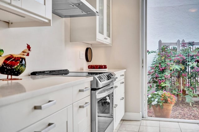 kitchen with white cabinetry, wall chimney exhaust hood, electric stove, and light tile patterned floors