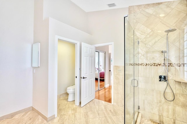 bathroom with a shower with door and toilet