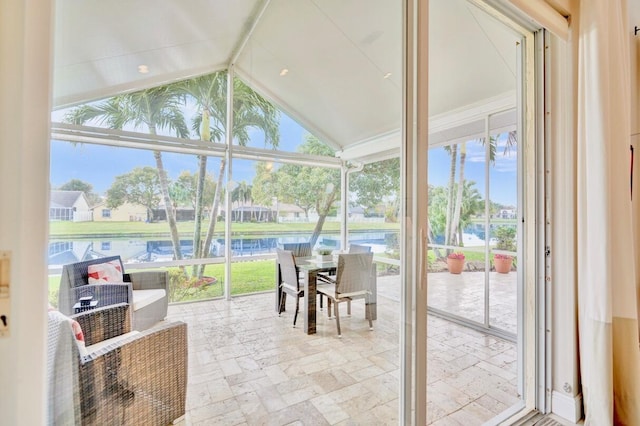 sunroom with lofted ceiling, a healthy amount of sunlight, and a water view