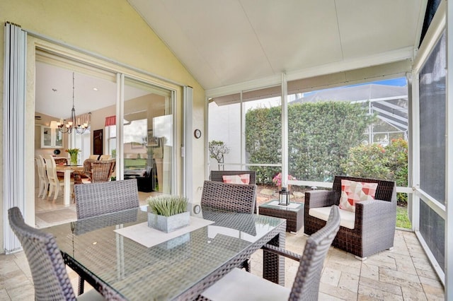 sunroom featuring vaulted ceiling and a chandelier